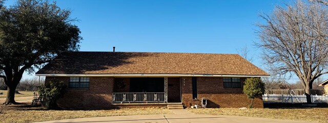 view of front of home featuring a porch, brick siding, and fence