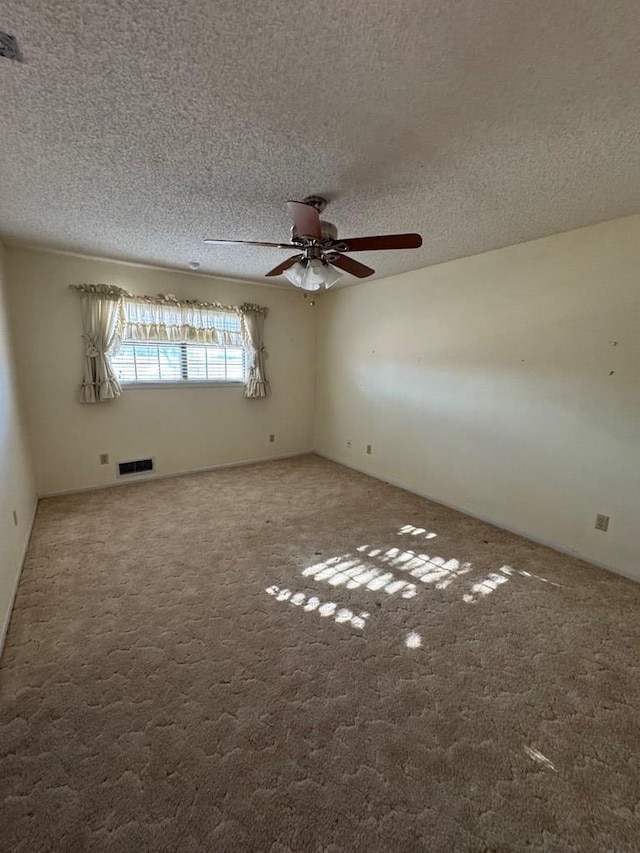 carpeted empty room with a textured ceiling, ceiling fan, and visible vents