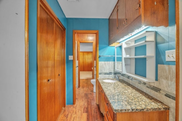 312 N Main St, Coahoma, TX 79511 - bathroom with wood finished floors, toilet, vanity, and decorative backsplash