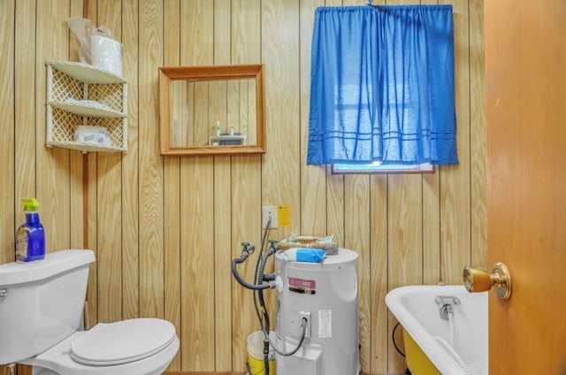 312 N Main St, Coahoma, TX 79511 - bathroom with toilet, a tub, electric water heater, and wooden walls