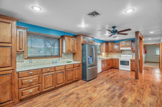 312 N Main St, Coahoma, TX 79511 - kitchen with a ceiling fan, brown cabinetry, decorative backsplash, white appliances, and under cabinet range hood