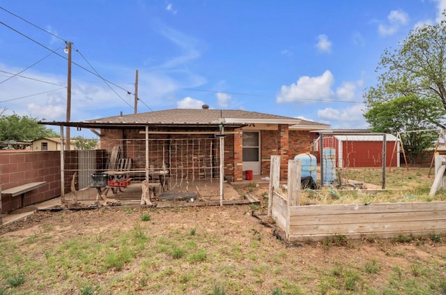 312 N Main St, Coahoma, TX 79511 - rear view of house with a vegetable garden, fence, an outbuilding, a storage unit, and brick siding