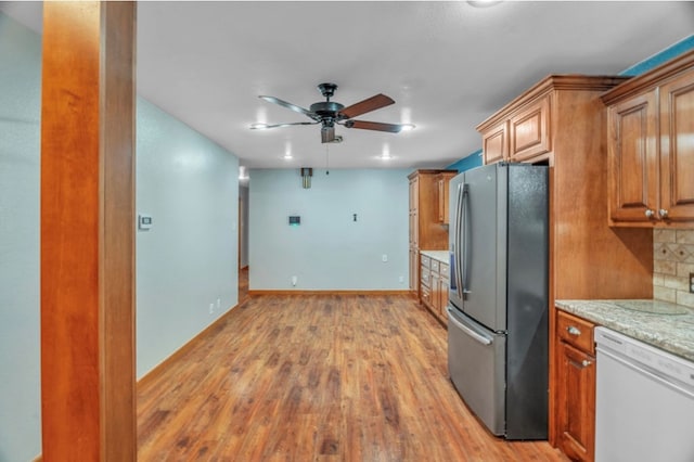 312 N Main St, Coahoma, TX 79511 - kitchen with brown cabinets, a ceiling fan, white dishwasher, light wood-type flooring, and stainless steel fridge