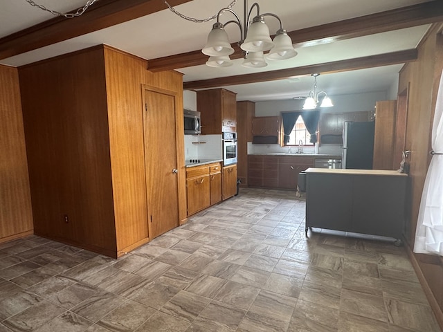 2615 W Golf Course Rd, Midland, TX 79705 - kitchen featuring a chandelier, appliances with stainless steel finishes, beamed ceiling, wood walls, and brown cabinetry