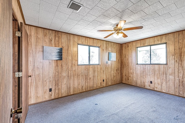 empty room featuring a wealth of natural light, ceiling fan, and light colored carpet