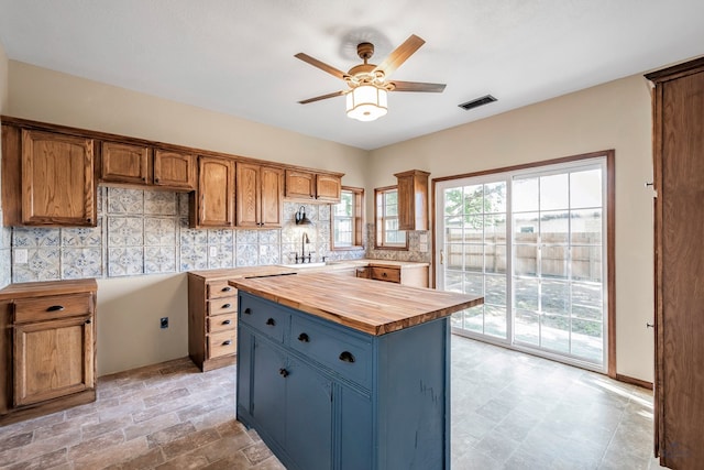 kitchen featuring wooden counters, a center island, ceiling fan, and sink