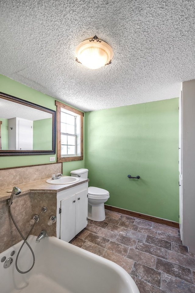 bathroom with vanity, a tub to relax in, and toilet