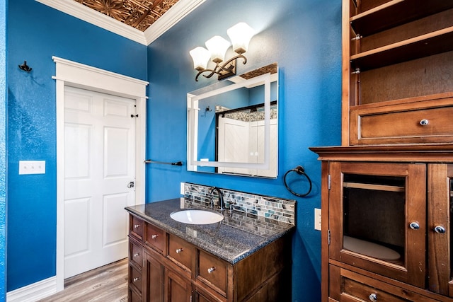 bathroom featuring backsplash, vanity, crown molding, and hardwood / wood-style flooring