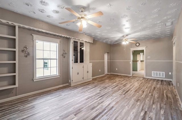 unfurnished room featuring a textured ceiling and light hardwood / wood-style flooring