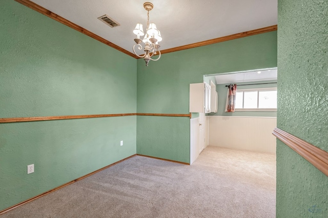 carpeted empty room featuring crown molding and a chandelier