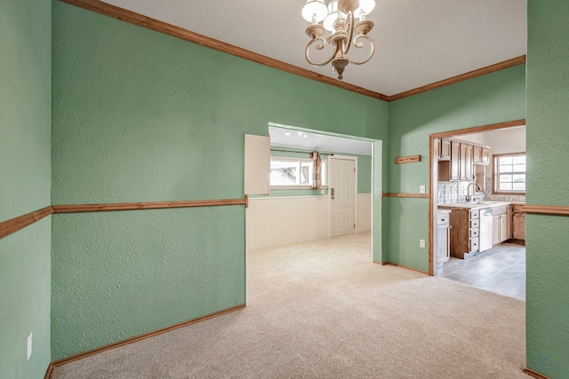 unfurnished room with a chandelier, crown molding, light colored carpet, and sink