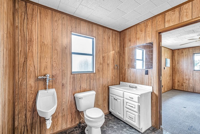 bathroom with wood walls, vanity, a healthy amount of sunlight, and toilet