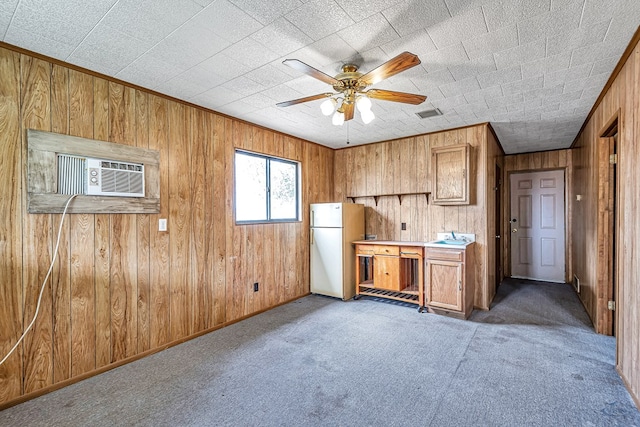 kitchen with a wall mounted AC, ceiling fan, wooden walls, carpet floors, and white fridge