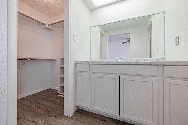 bathroom featuring a walk in closet, vanity, and wood finished floors