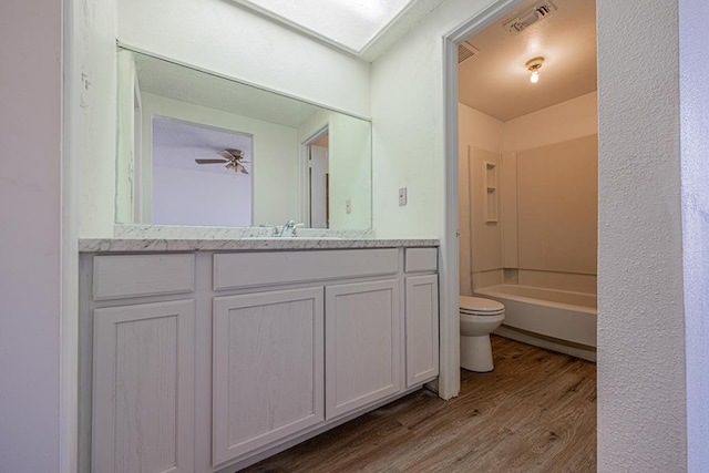 bathroom featuring visible vents, toilet, a ceiling fan, vanity, and wood finished floors