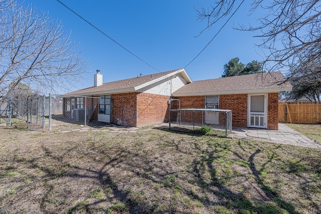 back of house with a patio, a chimney, a gate, fence, and brick siding