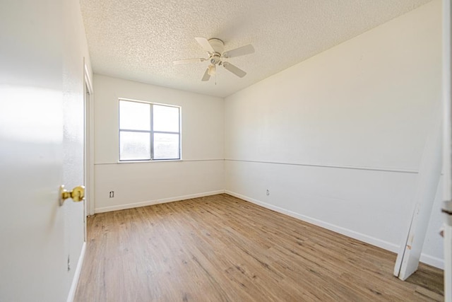 spare room featuring light wood-type flooring, ceiling fan, a textured ceiling, and baseboards