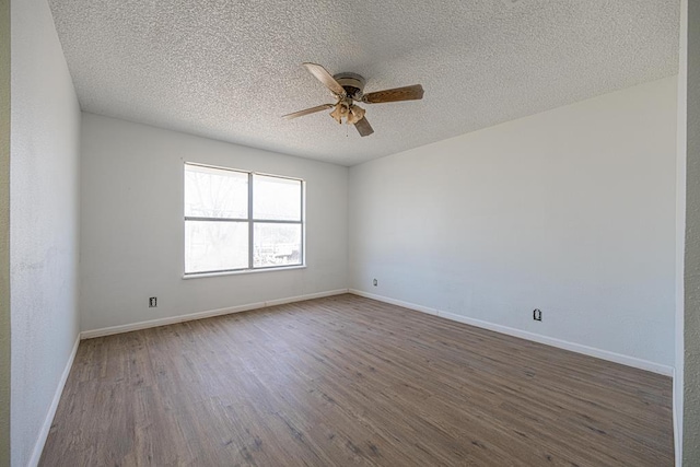 spare room featuring dark wood-style floors, a textured ceiling, a ceiling fan, and baseboards