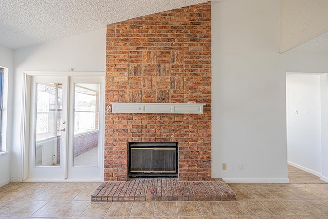 unfurnished living room featuring vaulted ceiling, a textured ceiling, a brick fireplace, and baseboards