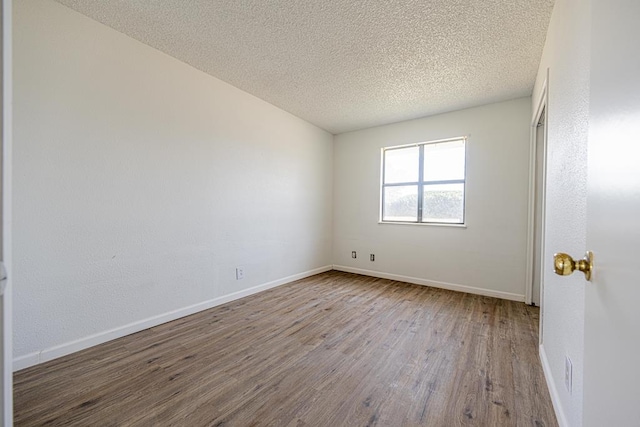 unfurnished room with a textured ceiling, baseboards, and wood finished floors