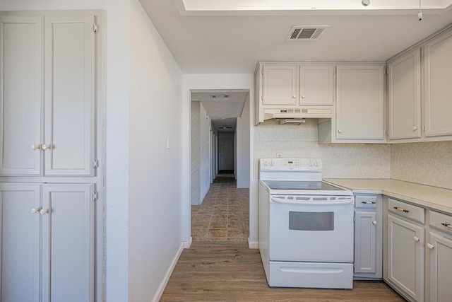 kitchen with white electric range oven, light countertops, visible vents, wood finished floors, and under cabinet range hood