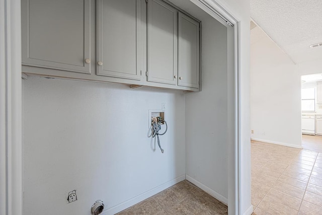 laundry room featuring cabinet space, baseboards, hookup for a washing machine, a textured ceiling, and hookup for an electric dryer