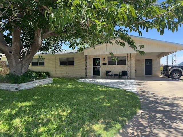 single story home with an attached carport, brick siding, driveway, and a front lawn