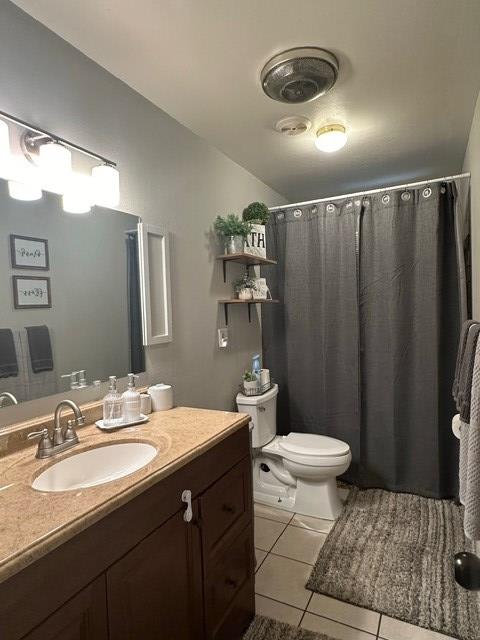 full bath with toilet, vanity, and tile patterned floors