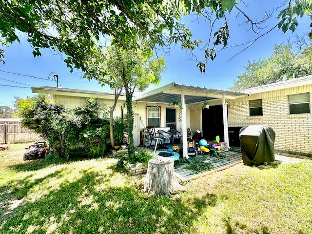 rear view of property with fence, a pergola, a lawn, and brick siding