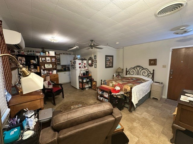 bedroom with freestanding refrigerator, visible vents, ceiling fan, and a wall unit AC