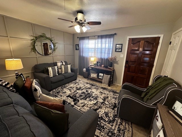 living area with ceiling fan and a decorative wall