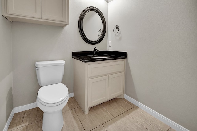 bathroom with toilet, vanity, baseboards, and tile patterned flooring