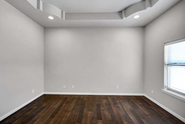 unfurnished room featuring a healthy amount of sunlight, baseboards, and dark wood finished floors