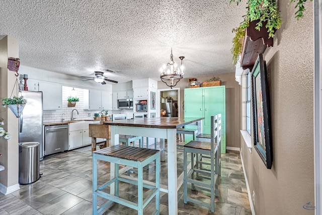 1412 Sparks St, Midland, TX 79701 - kitchen featuring appliances with stainless steel finishes, a chandelier, white cabinets, ceiling fan, and a sink