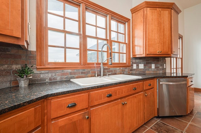 kitchen with backsplash, sink, dark tile patterned flooring, dark stone countertops, and dishwasher