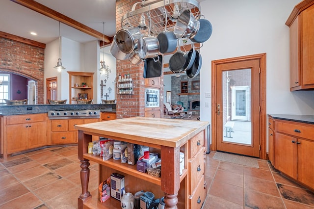 kitchen with brick wall, hanging light fixtures, beamed ceiling, stainless steel gas stovetop, and light tile patterned flooring