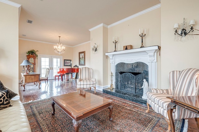 living room featuring french doors, ornamental molding, a premium fireplace, a chandelier, and hardwood / wood-style floors