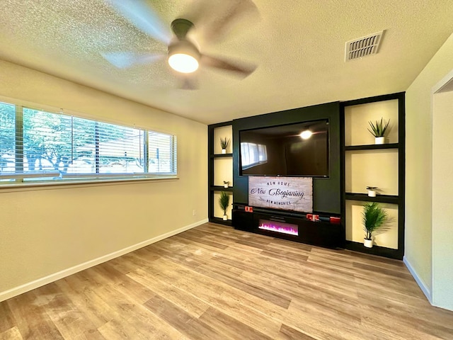 cinema room featuring ceiling fan, a textured ceiling, and light wood-type flooring