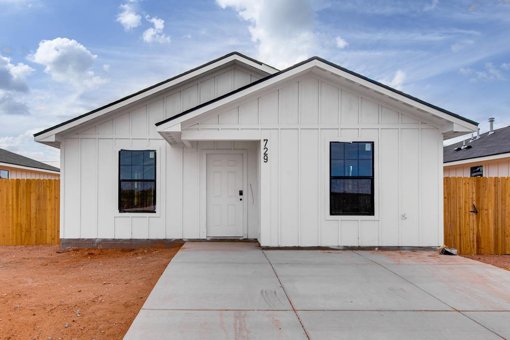 view of front of home with board and batten siding, a patio, and fence