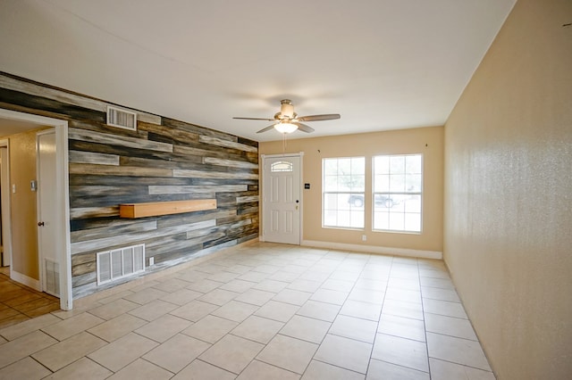 404W Jax Ave, Midland, TX 79701 - unfurnished living room featuring an accent wall, wood walls, ceiling fan, light tile patterned floors, and wallpapered walls