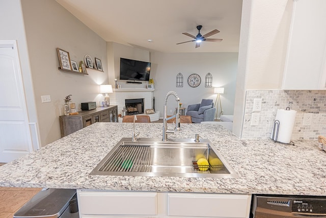 kitchen with a sink, open floor plan, tasteful backsplash, a ceiling fan, and white cabinets