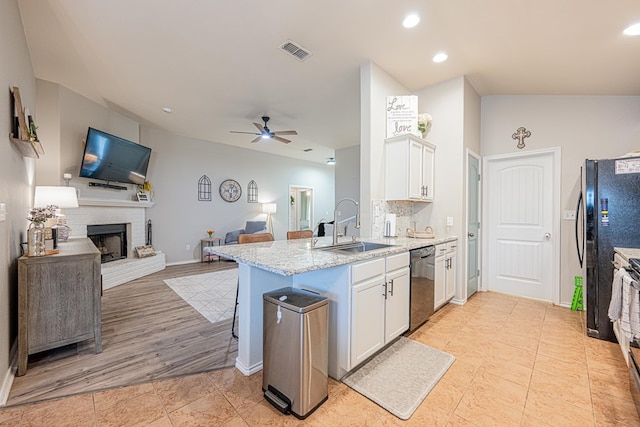kitchen featuring dishwasher, a sink, open floor plan, a peninsula, and recessed lighting