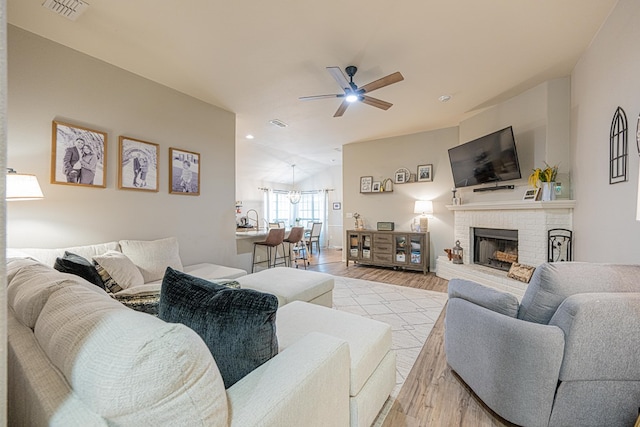 living room featuring a ceiling fan, light wood-style floors, and a fireplace