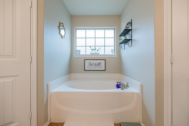 full bath featuring a garden tub and a textured wall