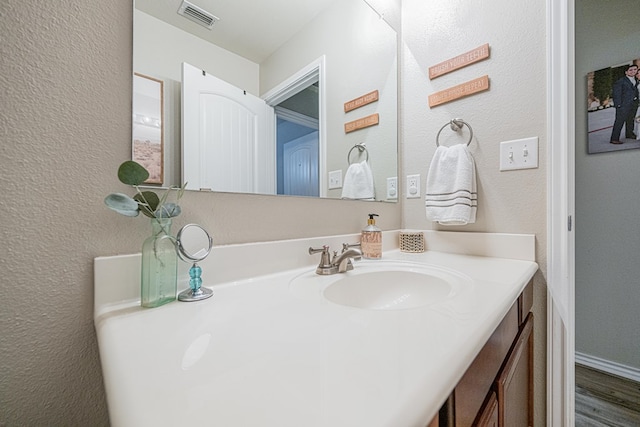 bathroom featuring vanity, a textured wall, and wood finished floors