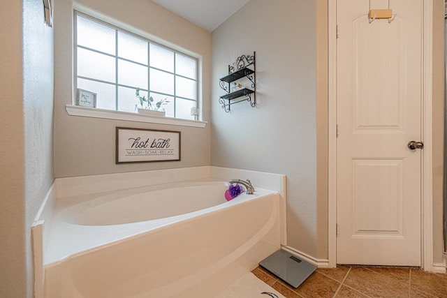 bathroom with a garden tub, tile patterned flooring, and baseboards