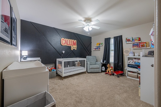 carpeted bedroom with a crib and a ceiling fan