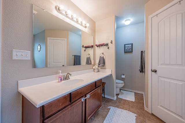bathroom with toilet, vanity, tile patterned floors, and baseboards