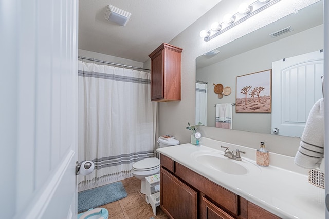 bathroom with toilet, vanity, and tile patterned flooring
