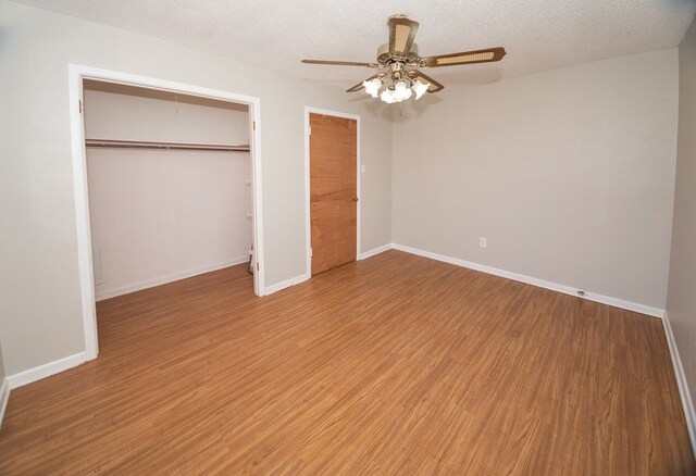 unfurnished bedroom with hardwood / wood-style flooring, a textured ceiling, a closet, and ceiling fan